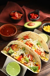 Delicious tacos with shrimps, cheese and lime on wooden table