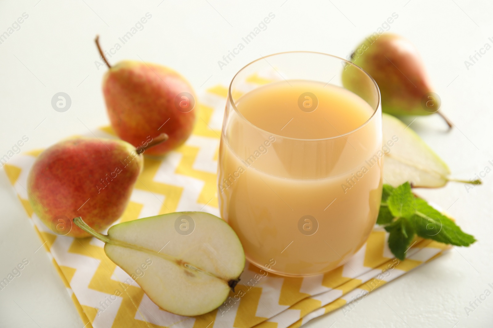 Photo of Tasty pear juice and fruits on white table, closeup