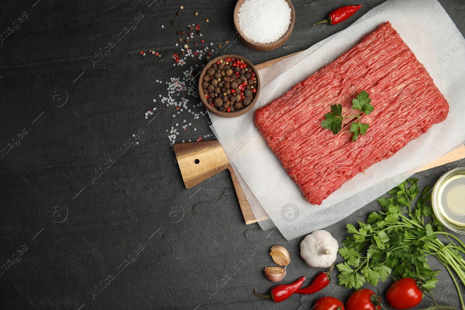 Photo of Raw fresh minced meat and other ingredients on black table, flat lay. Space for text