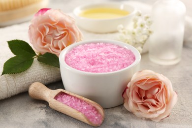 Photo of Pink sea salt and beautiful flowers on textured table, closeup
