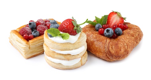 Fresh delicious puff pastries with sweet berries on white background