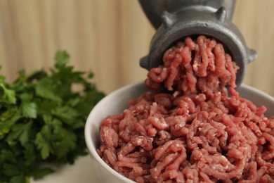 Photo of Mincing beef with manual meat grinder at table, closeup