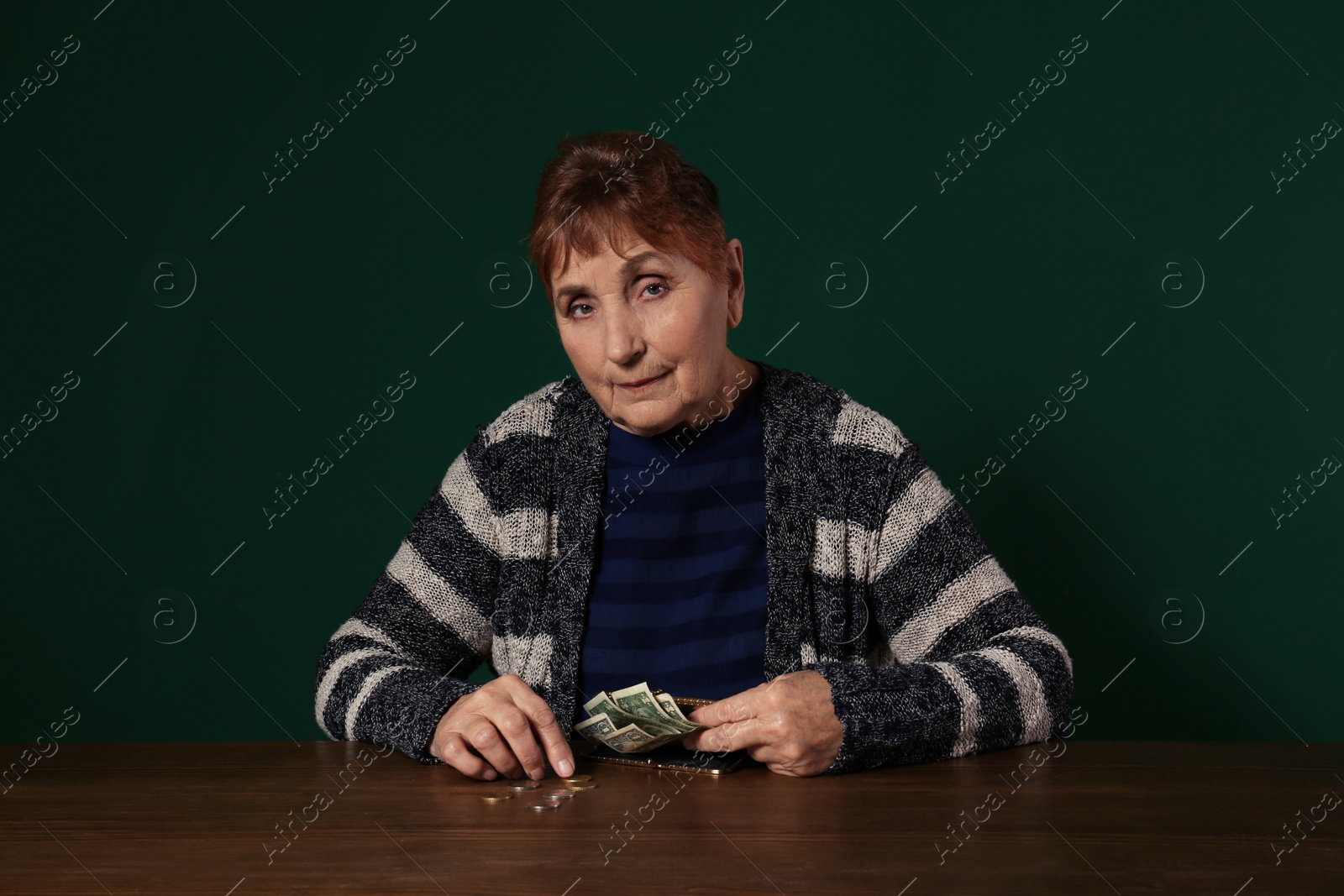 Photo of Poor senior woman with money at table against color background