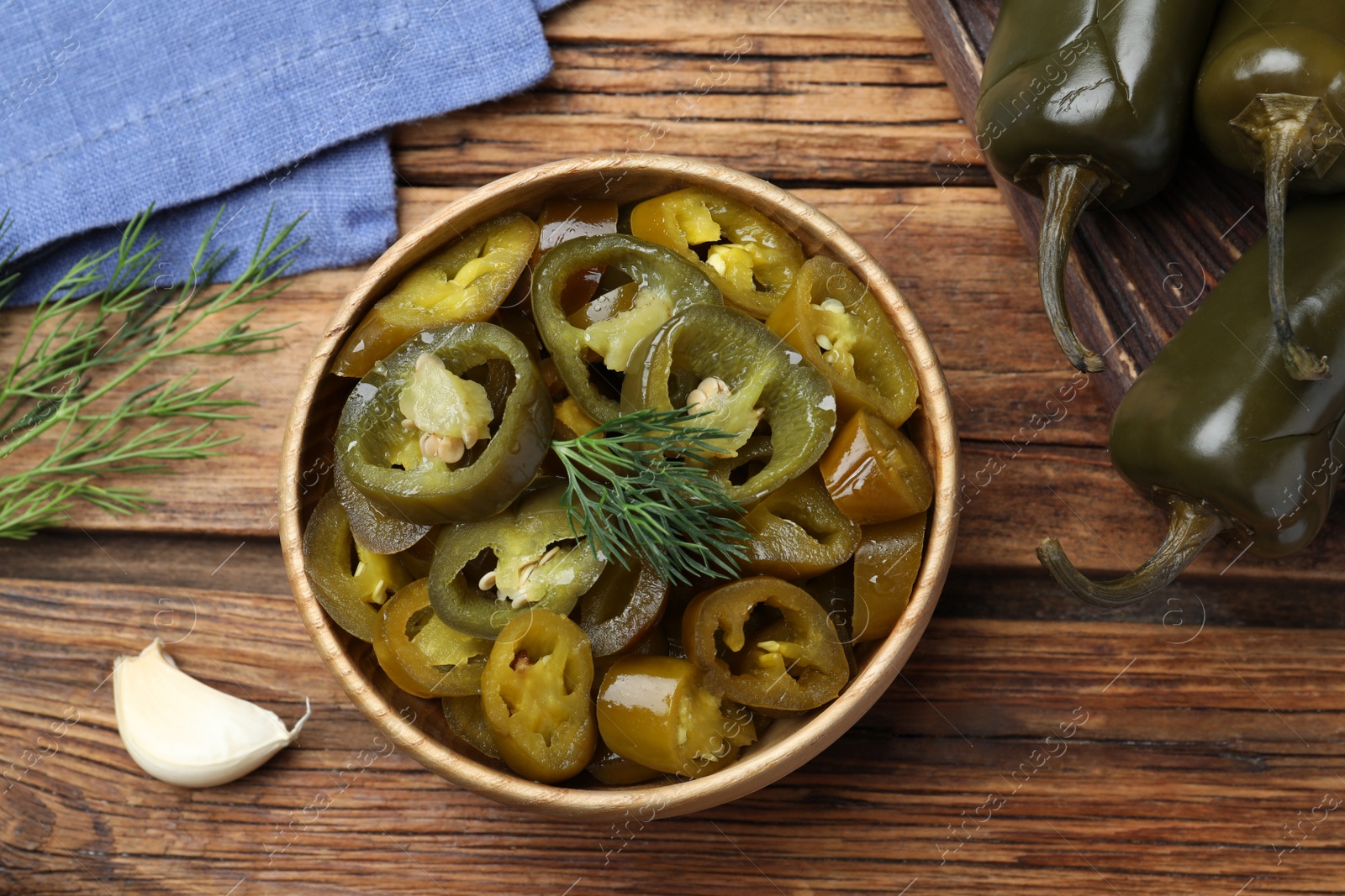 Photo of Flat lay composition with pickled green jalapeno peppers on wooden table