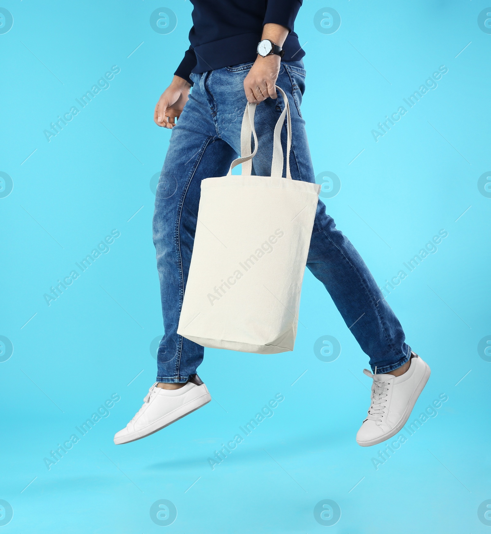 Photo of Young man holding textile bag on color background, closeup. Mockup for design