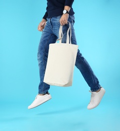 Young man holding textile bag on color background, closeup. Mockup for design