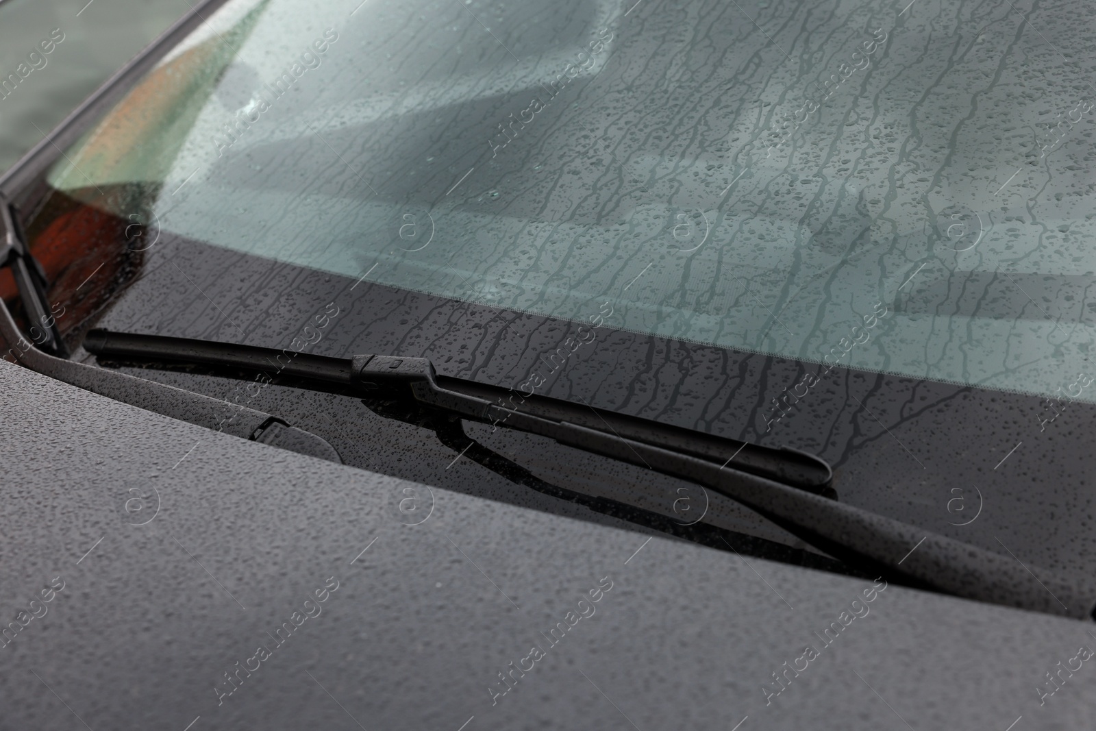 Photo of Car wipers cleaning water drops from windshield glass, closeup