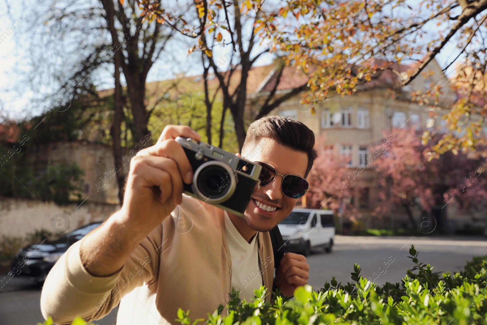 Photo of Happy male tourist with camera on city street