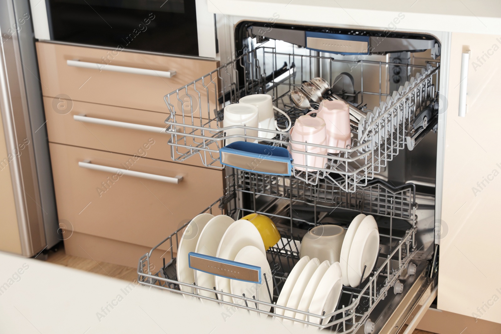 Photo of Open dishwasher with clean tableware in kitchen