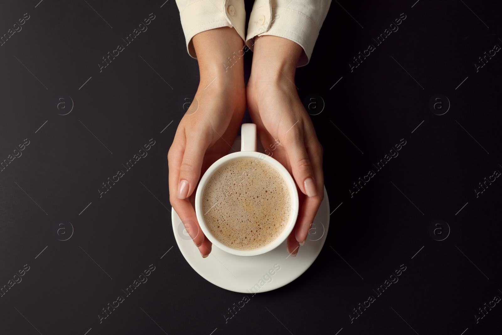 Photo of Woman with cup of coffee on black background, top view