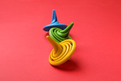 Many colorful spinning tops on red background, closeup