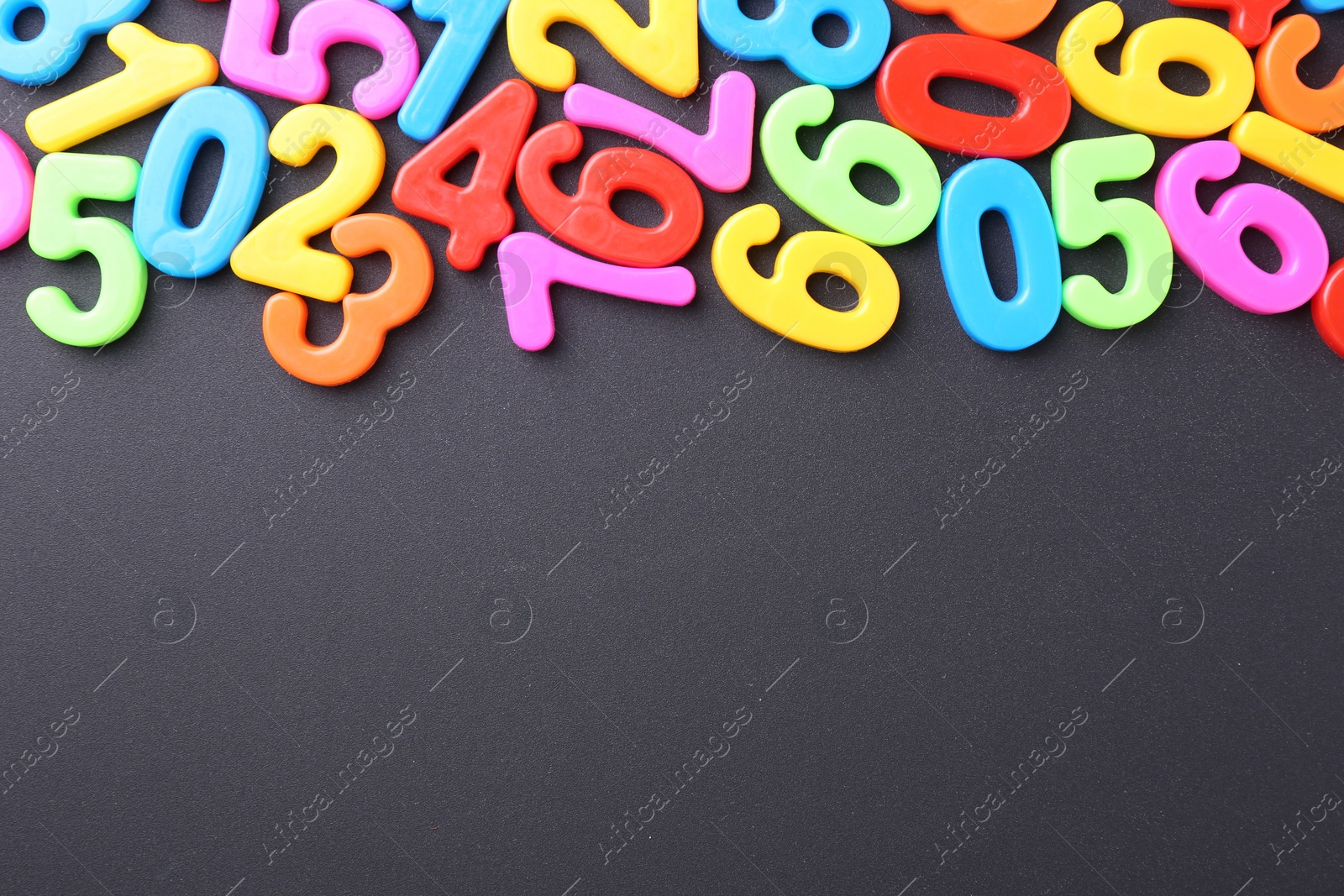 Photo of Colorful numbers on dark gray background, flat lay. Space for text