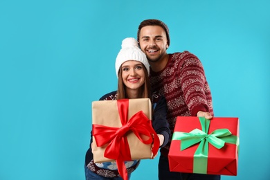 Photo of Couple in Christmas sweaters with gift boxes on blue background