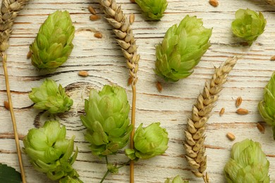 Flat lay composition with fresh green hops and wheat ears on white wooden table