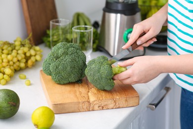 Photo of Woman cutting broccoli for smoothie in kitchen, closeup