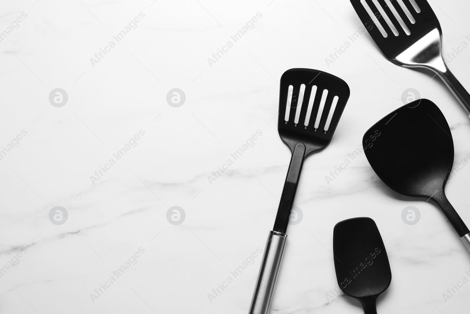 Photo of Different spatulas on white marble table, flat lay. Space for text