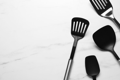 Photo of Different spatulas on white marble table, flat lay. Space for text