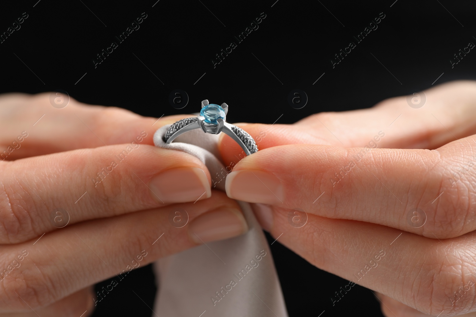 Photo of Jeweler cleaning topaz ring with microfiber cloth, closeup