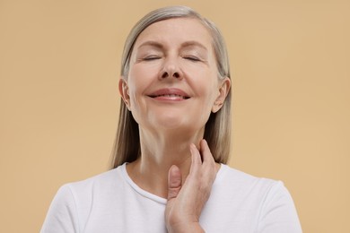 Photo of Beautiful woman touching her neck on beige background