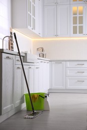 Photo of Floor mop, bucket and cleaning products in kitchen