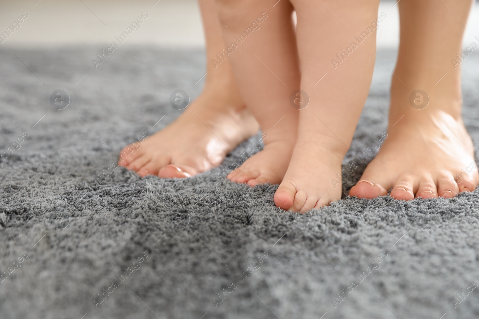 Photo of Mother and her baby standing on carpet, closeup of legs