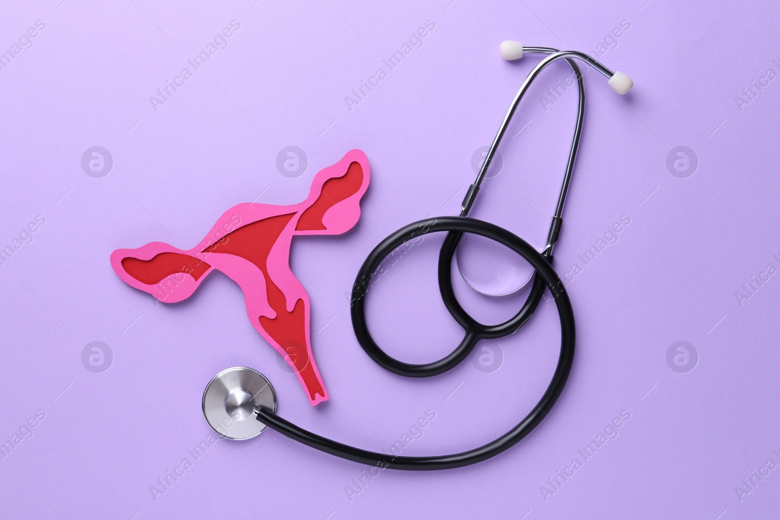 Photo of Reproductive medicine. Paper uterus and stethoscope on violet background, top view