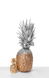 Photo of Silver and gold painted pineapple with cute decor on white background