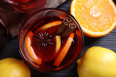 Photo of Aromatic punch drink and ingredients on black table, flat lay