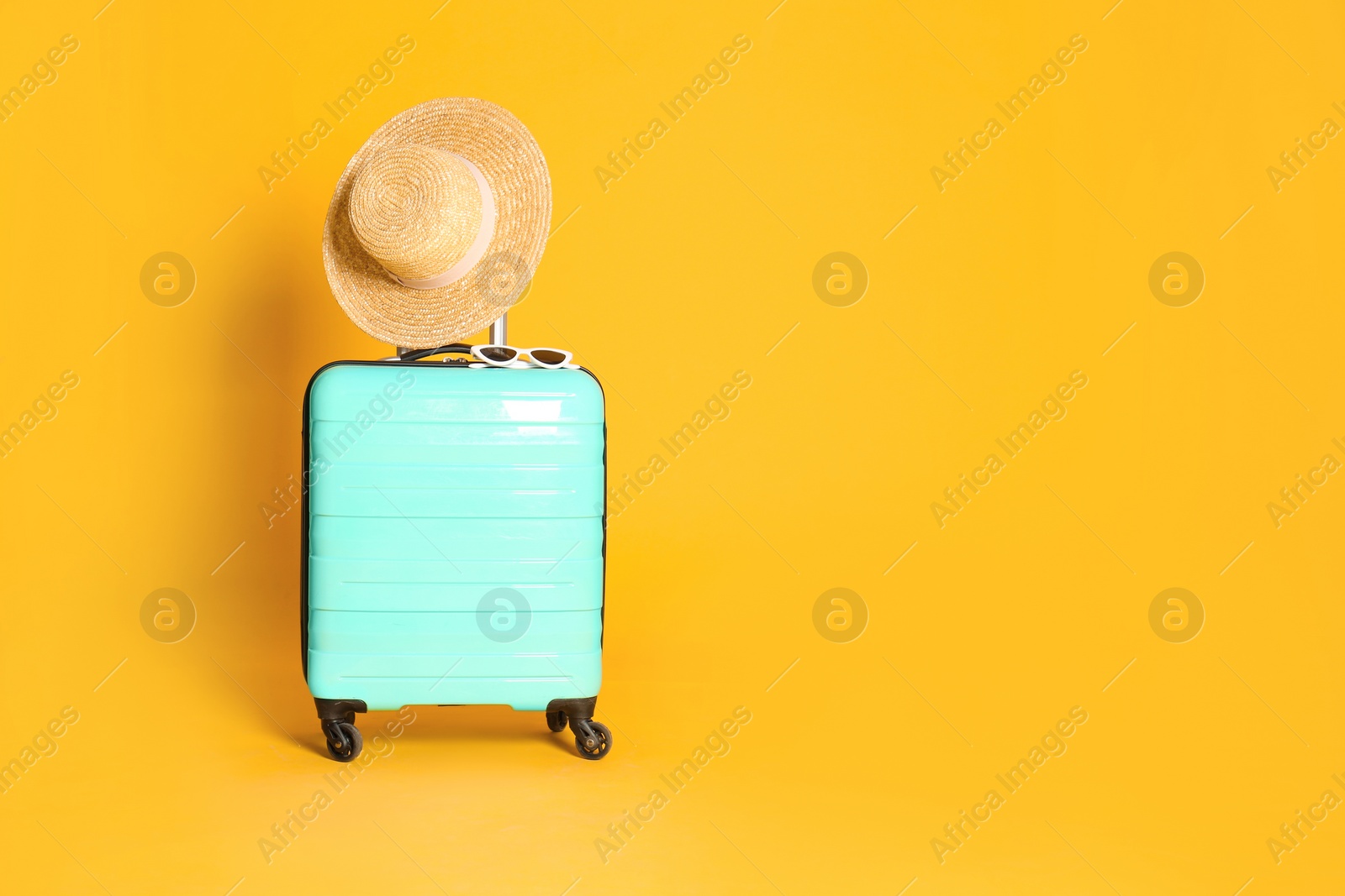 Photo of Travel suitcase with hat and sunglasses on yellow background, space for text. Summer vacation