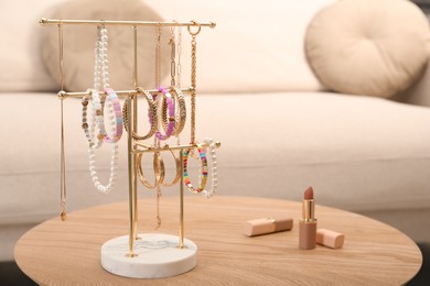 Photo of Holder with set of luxurious jewelry on wooden table in living room