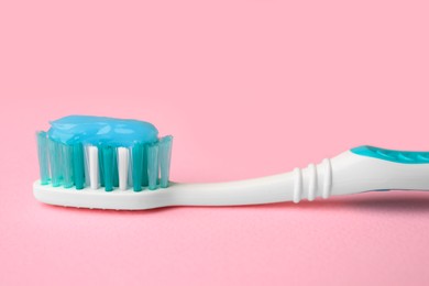 Photo of Brush and toothpaste on pink background, closeup