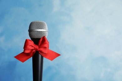 Photo of Microphone with bow on color background. Christmas music concept