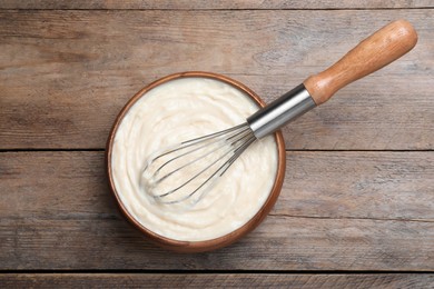 Pastry cream with balloon whisk on wooden table, top view