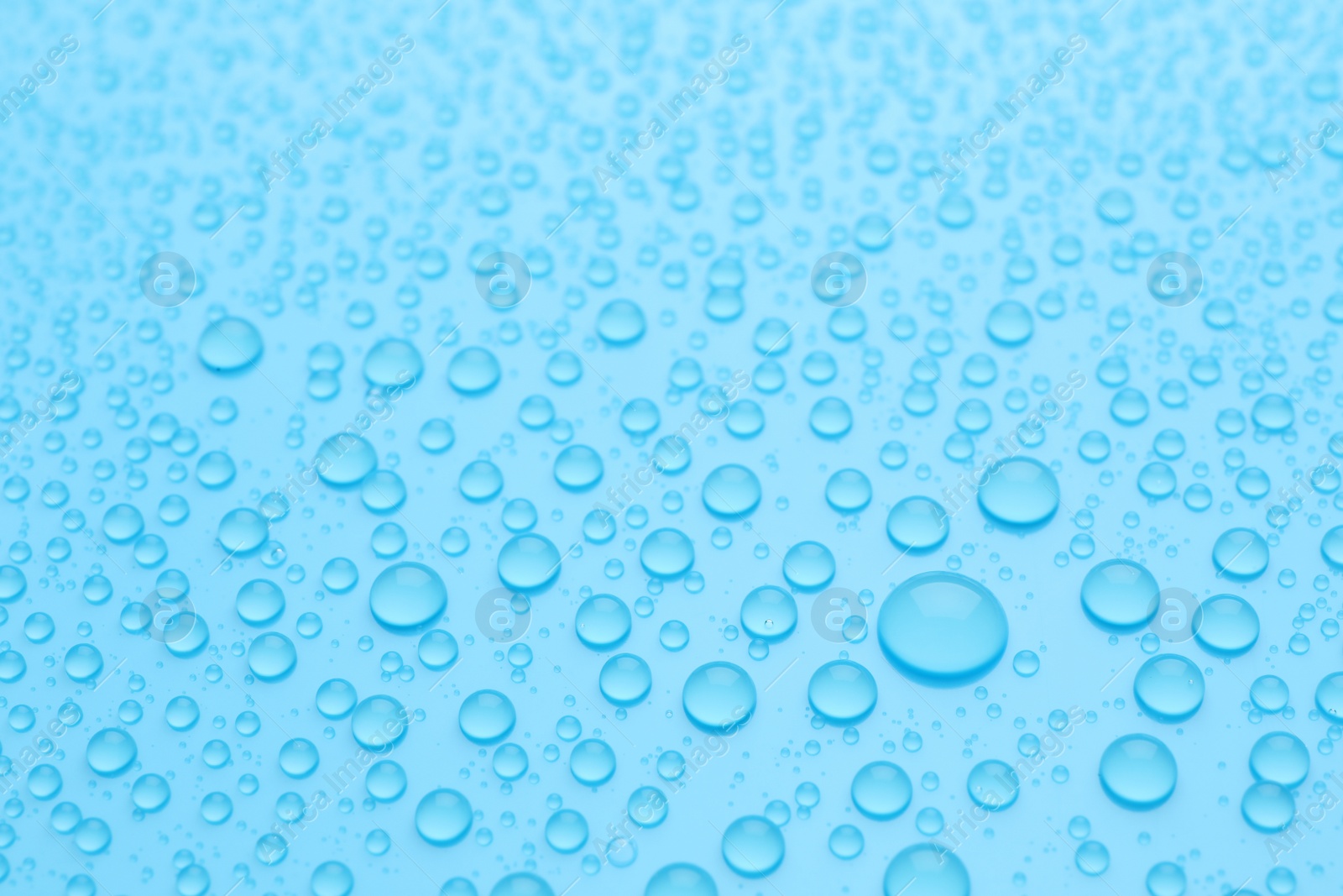 Photo of Water drops on light blue background, closeup view