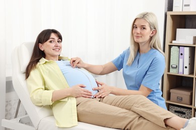Photo of Pregnancy checkup. Doctor measuring patient's tummy in clinic