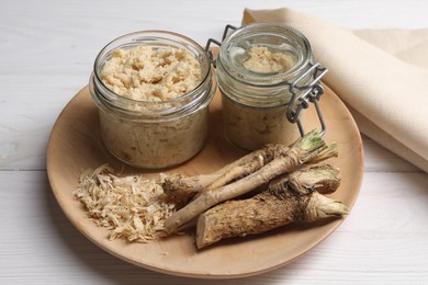 Photo of Platter with tasty prepared horseradish and roots on white wooden table