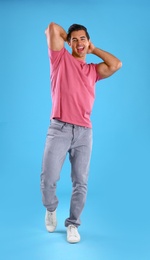 Photo of Handsome young man dancing on blue background