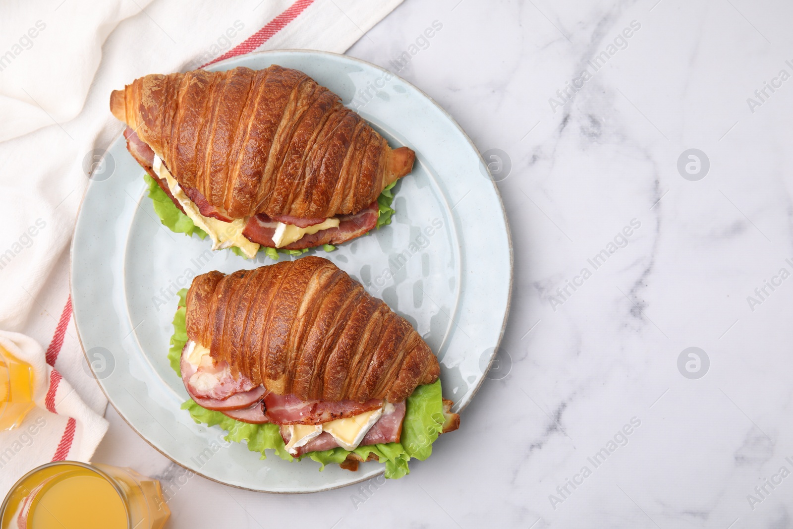 Photo of Tasty croissants with brie cheese, ham and bacon on white marble table, flat lay. Space for text