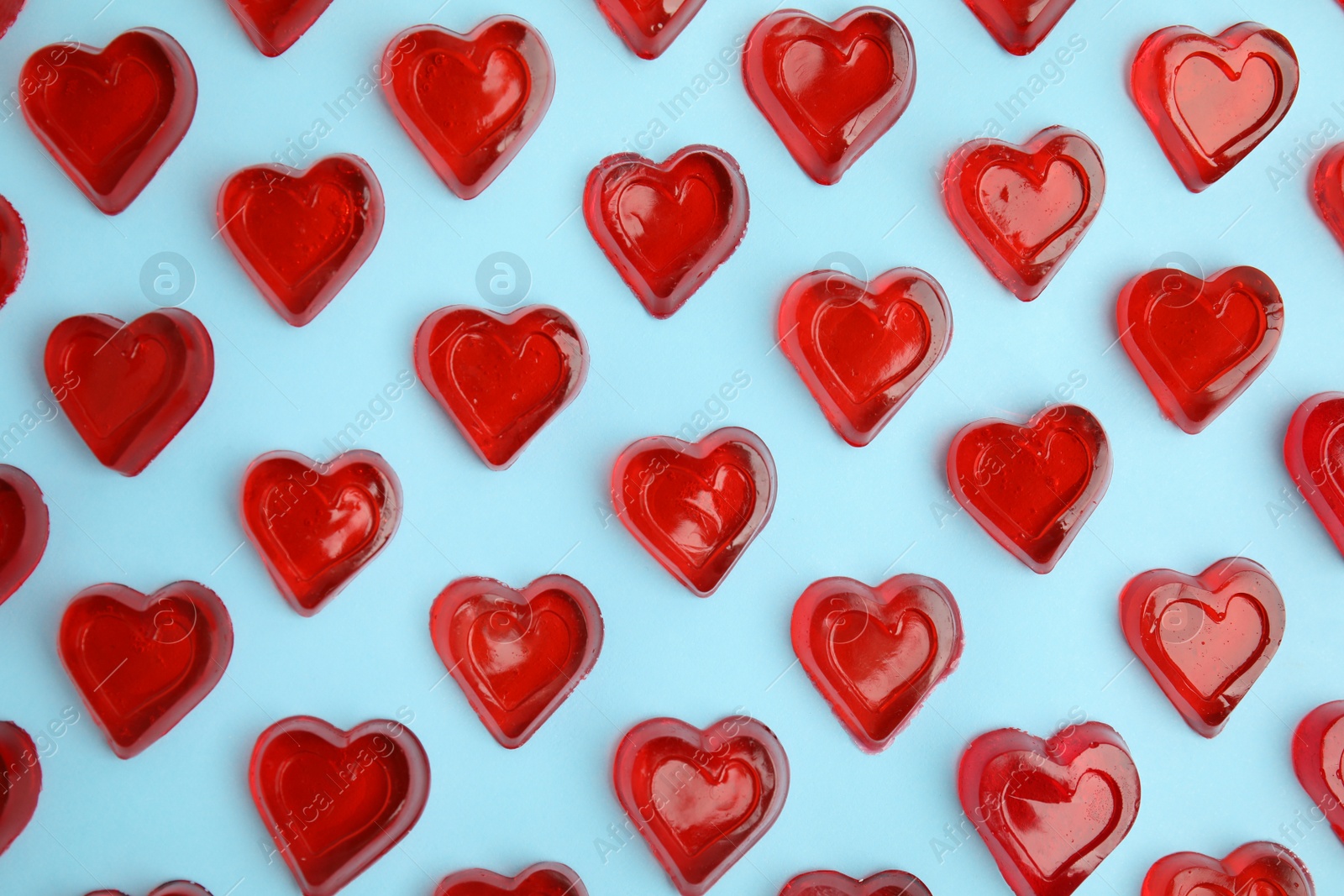 Photo of Sweet heart shaped jelly candies on light blue background, flat lay