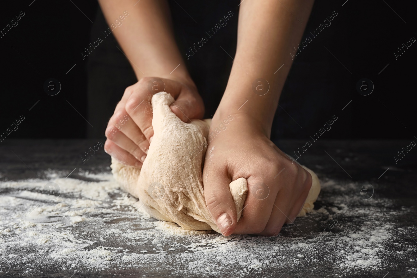 Photo of Young woman kneading dough at table, closeup