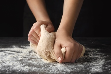 Photo of Young woman kneading dough at table, closeup