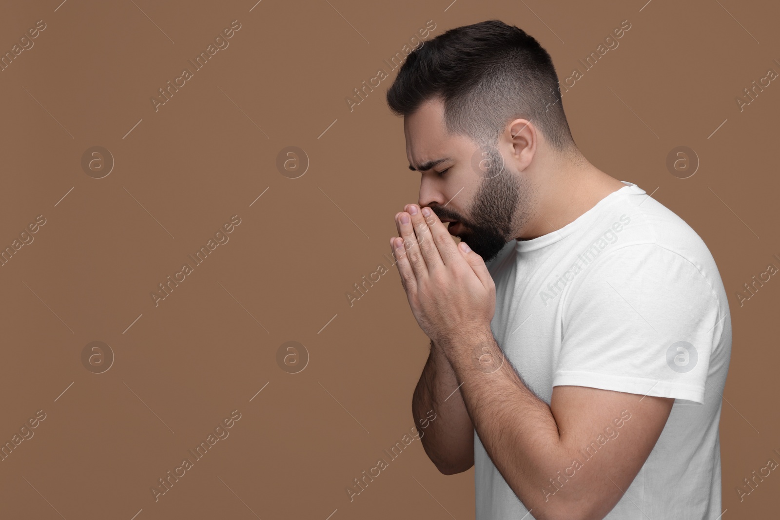 Photo of Sick man coughing on brown background, space for text