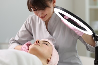 Photo of Cosmetologist making face massage to client in clinic