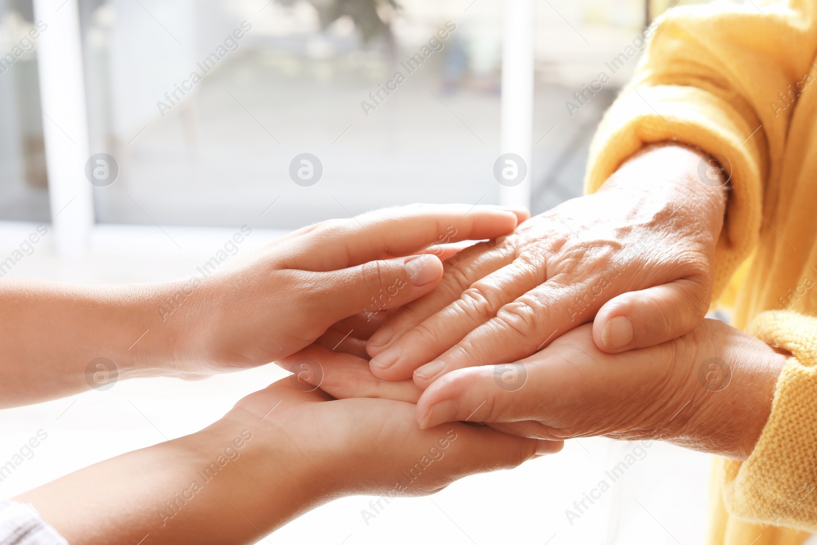 Photo of Helping hands on blurred background, closeup. Elderly care concept