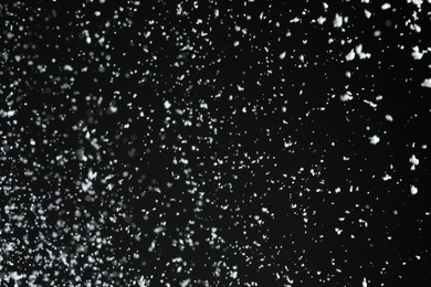 Photo of White snow falling down on black background