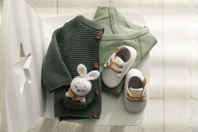 Baby clothes, shoes and toy on chair indoors, top view