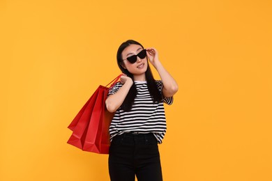 Photo of Beautiful woman with shopping bags on yellow background