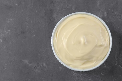 Photo of Fresh mayonnaise sauce in bowl on grey table, top view. Space for text