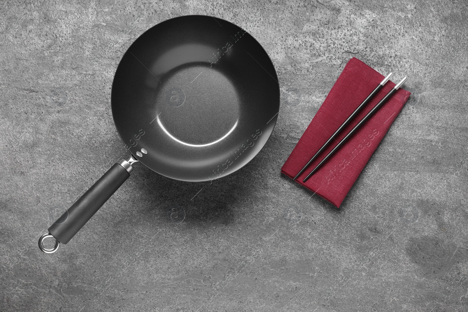 Photo of Empty iron wok and chopsticks on grey table, flat lay