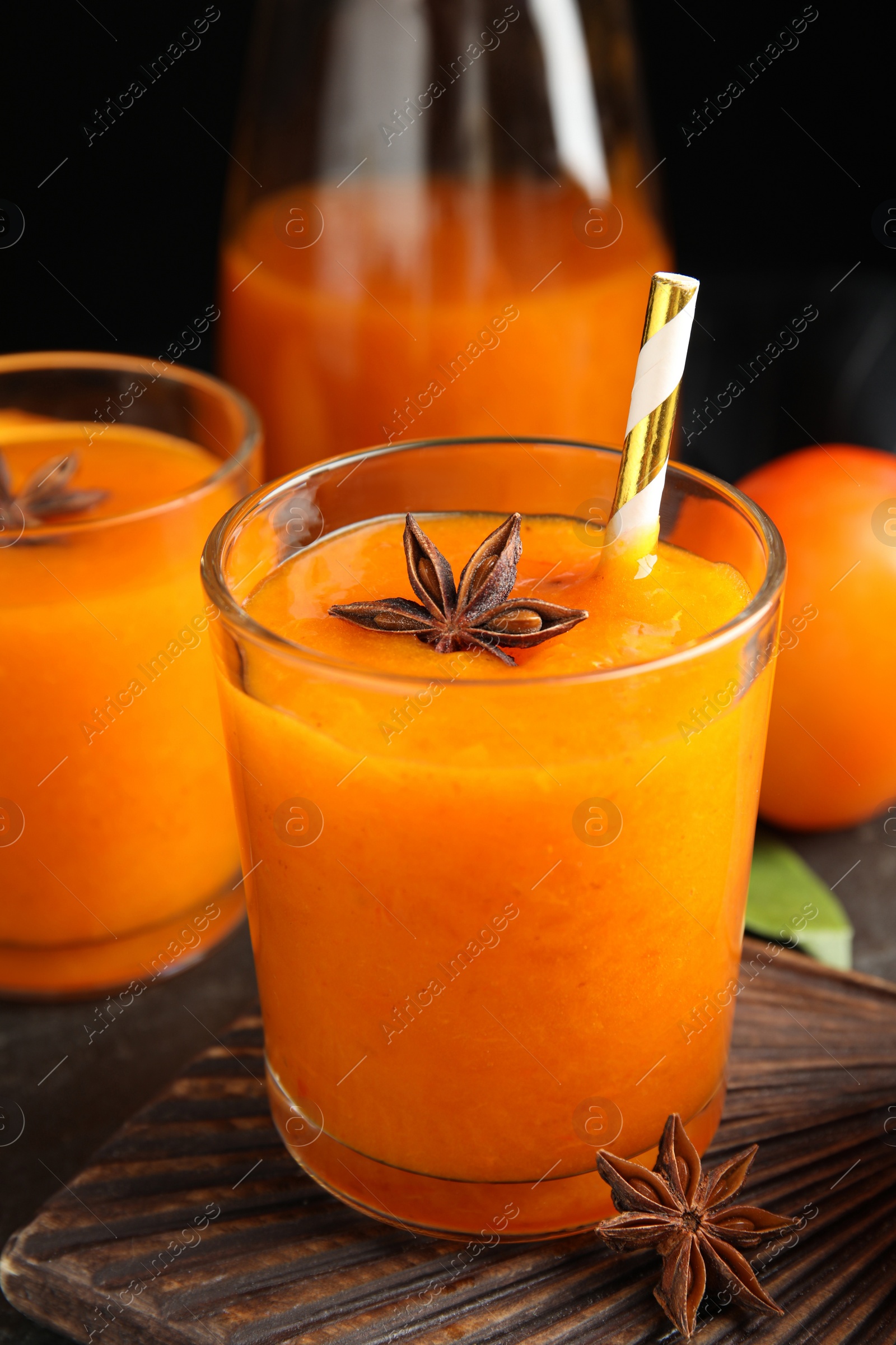 Photo of Tasty persimmon smoothie with anise on wooden board, closeup